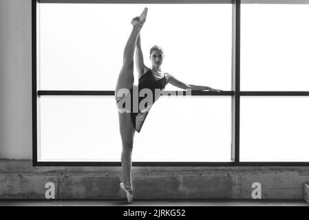 Foto der jungen Ballerina, die im Tanzstudio auf Zehenspitzen posiert Stockfoto