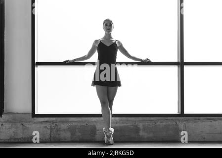 Foto der jungen Ballerina, die im Tanzstudio auf Zehenspitzen posiert Stockfoto