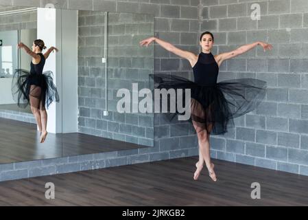 Foto der jungen Ballerina, die im Tanzstudio auf Zehenspitzen posiert Stockfoto