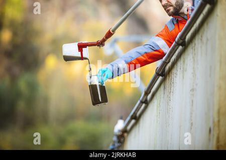 Kläranlage, Techniker, der eine Wasserprobe in einem Sedimentationstank zur Analyse sammelt Stockfoto