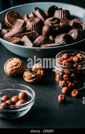 Verschiedene handgemachte Pralinen mit Nüssen auf schwarzem Tisch angeordnet Stockfoto