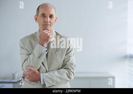 Porträt eines lächelnden, selbstbewussten und erfahrenen Geschäftsmannes in seinem Büro Stockfoto