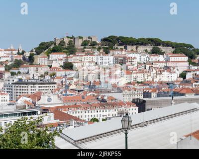 Blick vom Aussichtspunkt (Miradouro) São pedro de Alcântara in Lissabon, Portugal an einem Sommerabend über den Dächern der Stadt. Schloss St. Georges dahinter. Stockfoto