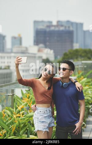 Umarmt junges vietnamesisches Paar, das Selfie im Freien nimmt Stockfoto