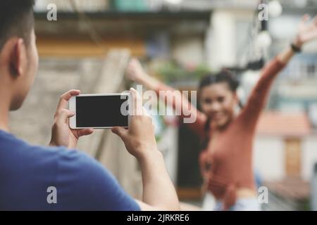 Nahaufnahme eines Mannes, der eine Freundin auf seinem Handy fotografiert Stockfoto