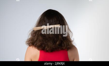 Kamm steckt in den matten Haaren einer Frau, Kratzprobleme Stockfoto