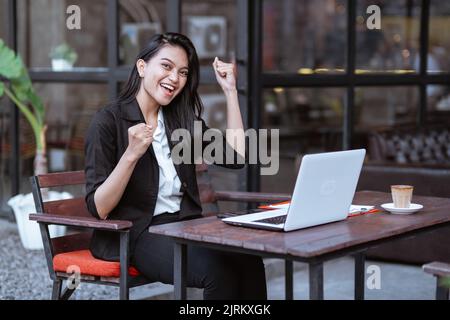 Eine Mitarbeiterin war begeistert, als sie alleine im Café draußen arbeitete Stockfoto