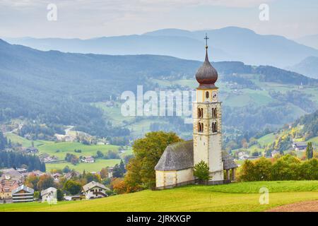 St. Valentin Kastelruth Dorfkirche im Sommer in den Dolomiten. Herrliche Landschaft mit kleiner Kapelle auf sonniger Wiese und Petzgipfel bei Kastel Stockfoto