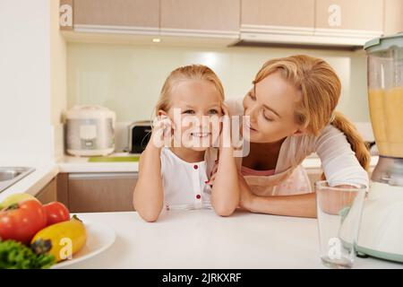 Lächelnde Mutter und Tochter im Gespräch in der Küche Stockfoto