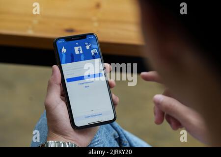 CHIANG MAI, THAILAND - AUG 25, 2022 : Ein Mann hält Apple iPhone mit facebook-Anwendung auf dem Bildschirm.facebook ist eine Foto-Sharing-App für Smartphones Stockfoto