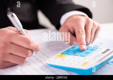 Ein Finger, der Zahlen mithilfe eines Taschenrechners in Nahaufnahme addiert Stockfoto