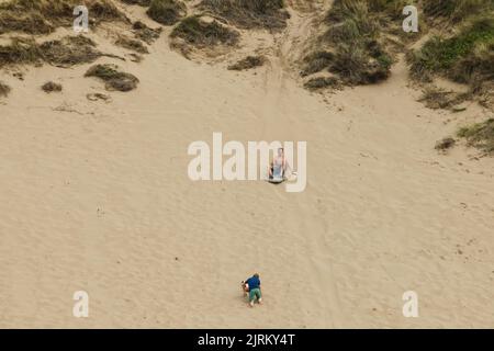 Surfen Sie am Strand entlang der Sanddünen am Woolacombe Beach, North Devon, England, Großbritannien Stockfoto