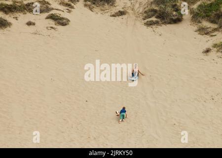 Surfen Sie am Strand entlang der Sanddünen am Woolacombe Beach, North Devon, England, Großbritannien Stockfoto