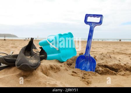 Eimer und Spaten mit Sandschuhen am Woolacombe Beach, North Devon, England, Großbritannien Stockfoto