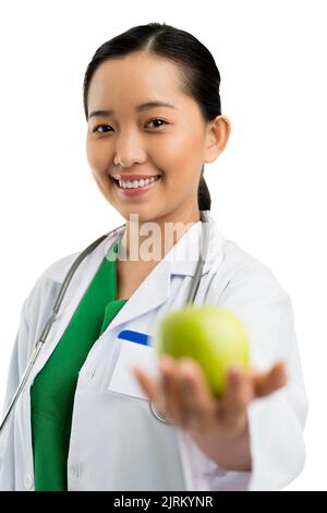 Lächelnder hübscher vietnamesischer Arzt, der Ihnen grünen Apfel gibt Stockfoto