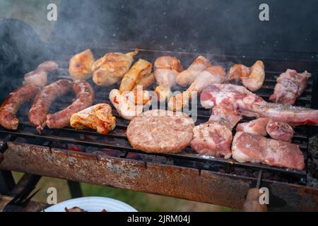 Verschiedene köstliche gegrillte Fleisch mit Gemüse über den Kohlen auf einem Grill Stockfoto
