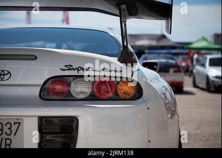 Nahaufnahme des Hecks eines weißen Toyota Supra der vierten Generation mit Kohlefaserspoiler und unscharfem Hintergrund Stockfoto