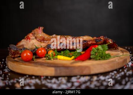 Nahaufnahme von Rippchen vom Grill mit BBQ Sauce und karamellisierten in Honig. Leckeren Snack zum Bier auf einem Holzbrett für die Einreichung auf dunklen konkreten Hintergrund Stockfoto