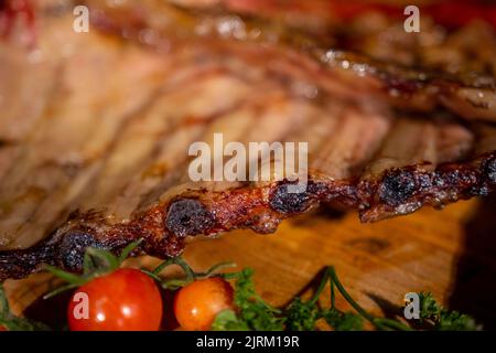 Nahaufnahme von Rippchen vom Grill mit BBQ Sauce und karamellisierten in Honig. Leckeren Snack zum Bier auf einem Holzbrett für die Einreichung auf dunklen konkreten Hintergrund Stockfoto