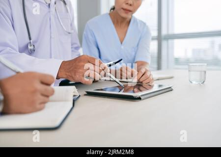 Zugeschnittenes Bild von Medizinern, die Informationen auf einem Tablet-Computer diskutieren Stockfoto