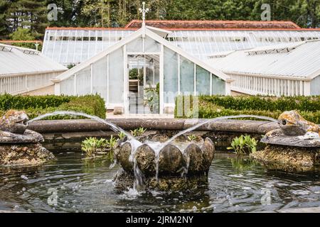 Der Zierbrunnen und die grünen Häuser im Hintergrund der Eythrope Gardens auf dem Landgut Waddesdon. Stockfoto