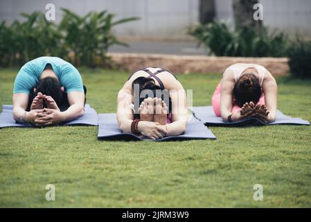 Flexible Yuong-Menschen, die sich nach vorne strecken und auf ihren Beinen liegen Stockfoto