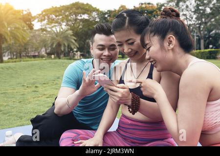 Freunde sehen sich nach dem Yoga-Training lustige Videos auf dem Smartphone an Stockfoto