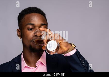 Junger schwarzer Mann schlürft Wein Stockfoto