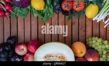 Obst und Gemüse mischen sich in Form eines Rahmens auf einem hölzernen Hintergrund mit Platz für die Beschriftung Stockfoto
