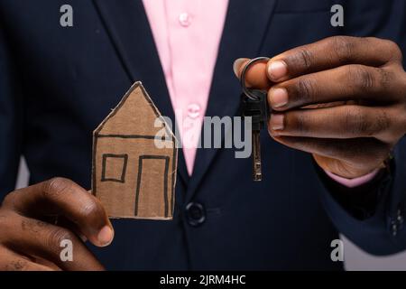 afrikanischer Mann mit Papphaus und Schlüssel Stockfoto