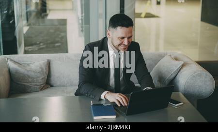 Erfolgreicher Geschäftsmann, der zur Mittagszeit in einem stilvollen Café mit Laptop-Rechenleistung unterwegs war. Er fand es Stockfoto