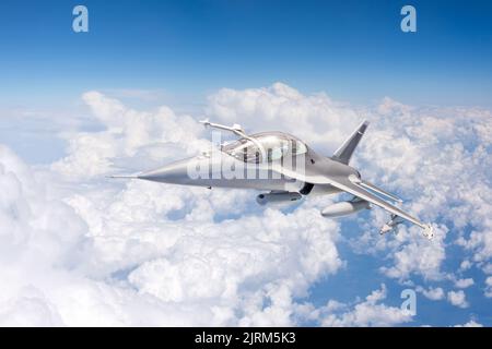 Hinter Kumuluswolken fliegt ein heimlicher Tarnjäger hoch am Himmel Stockfoto