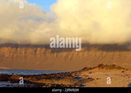 Blick auf den Risco de Famara vom Strand San Juan bei Sonnenuntergang Stockfoto