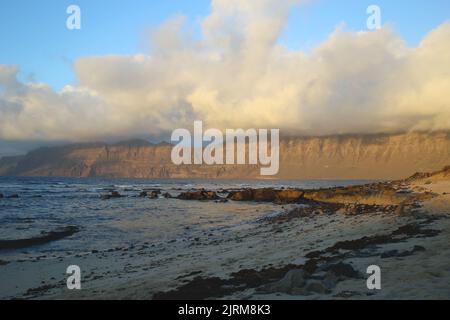 Blick auf den Risco de Famara vom Strand San Juan bei Sonnenuntergang Stockfoto