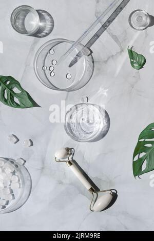 Hausgemachte Feuchtigkeitscreme und weiße Stein Gesichtswalzen auf weißem Marmor Hintergrund. Stockfoto