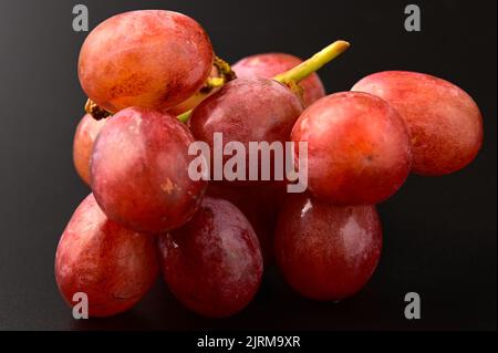 Ein Strauß roter Trauben auf schwarzem Hintergrund Stockfoto