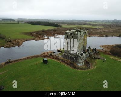 Eine High-Angle-Aufnahme des Schlosses Dunguaire am Flussufer mit Feldern und Himmel im Hintergrund Stockfoto