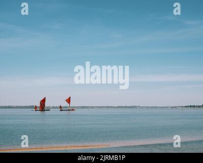 Zwei historische, rot segelte Thames Sailing-Lastkähne, die entlang der Schwarzwassermündung am Bradwell Waterside, Bradwell on Sea, Essex England, fahren Stockfoto