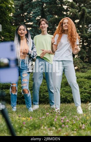 Drei Freunde im Stadtpark versuchen, ein Video aus sozialen Netzwerken zu kopieren. Spaß im Freien, via Online. Anfänger Blogger Stockfoto