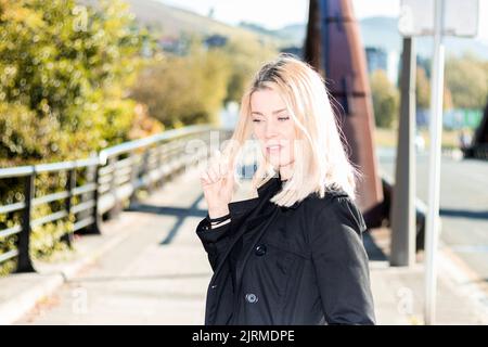 Schöne blonde Frau berührt ihre Haare in einem Park Stockfoto