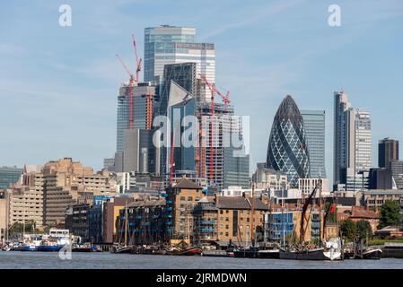 Die Skyline des neuen Finanzviertels von London hinter den Ufergrundstücken der Themse. Der Skalpell, 22 Bishopsgate, Gherkin & Baukräne. Boote Stockfoto