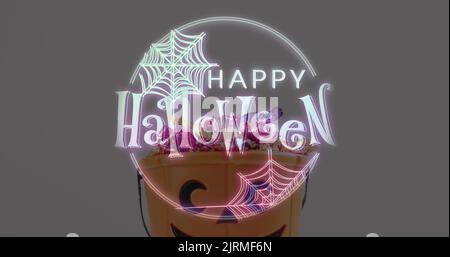 Halloween-Textbanner mit Spinnennetz-Symbol gegen Kürbis geformten Eimer voller halloween-Süßigkeiten Stockfoto