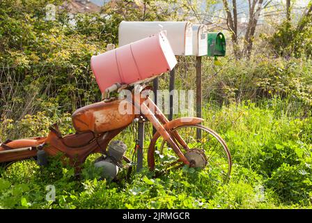 Recycelte Retro-Briefkästen mit alten rostigen Vintage-Motorrad auf dem Land Stockfoto