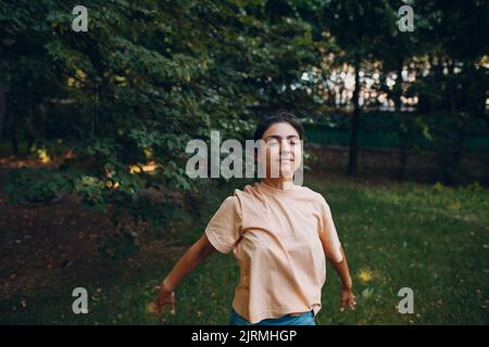 Sportliche Millennial Indian Woman in Freizeitkleidung Stretching vor dem Training im Park, Aufwärmübungen. Stockfoto