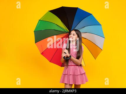 Sommerkleid. Happy teen Mädchen hält Regenbogen-umbella isoliert auf gelbem Hintergrund, isoliert auf weiß. Fröhlicher Teenager Kind halten Sonnenschirm. Stockfoto