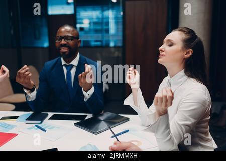 Das Team von Geschäftsleuten meditiert und hält sich nach dem Büromeeting die Hände. Business People Group Konferenz Diskussion Meditationskonzept Stockfoto