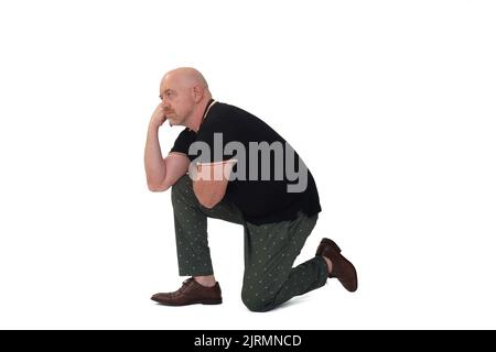 Profilansicht eines Mannes, der mit dem Knie auf dem Boden sitzt und denkt Stockfoto