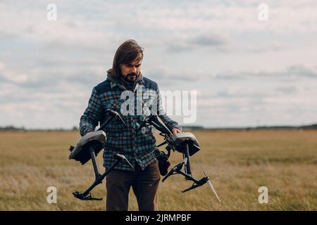 Mann Pilot hält Quadcopter Drohne in den Händen auf dem Außenfeld Stockfoto