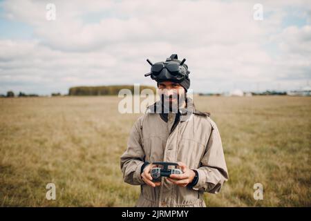 Mann, der die fpv-Quadcopter-Drohne für Luftaufnahmen und Videoaufnahmen mit einer Brillenantenne-Fernbedienung steuert. Stockfoto