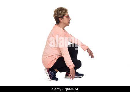 Seitenansicht einer älteren Frau, die auf weißem Hintergrund hockt Stockfoto